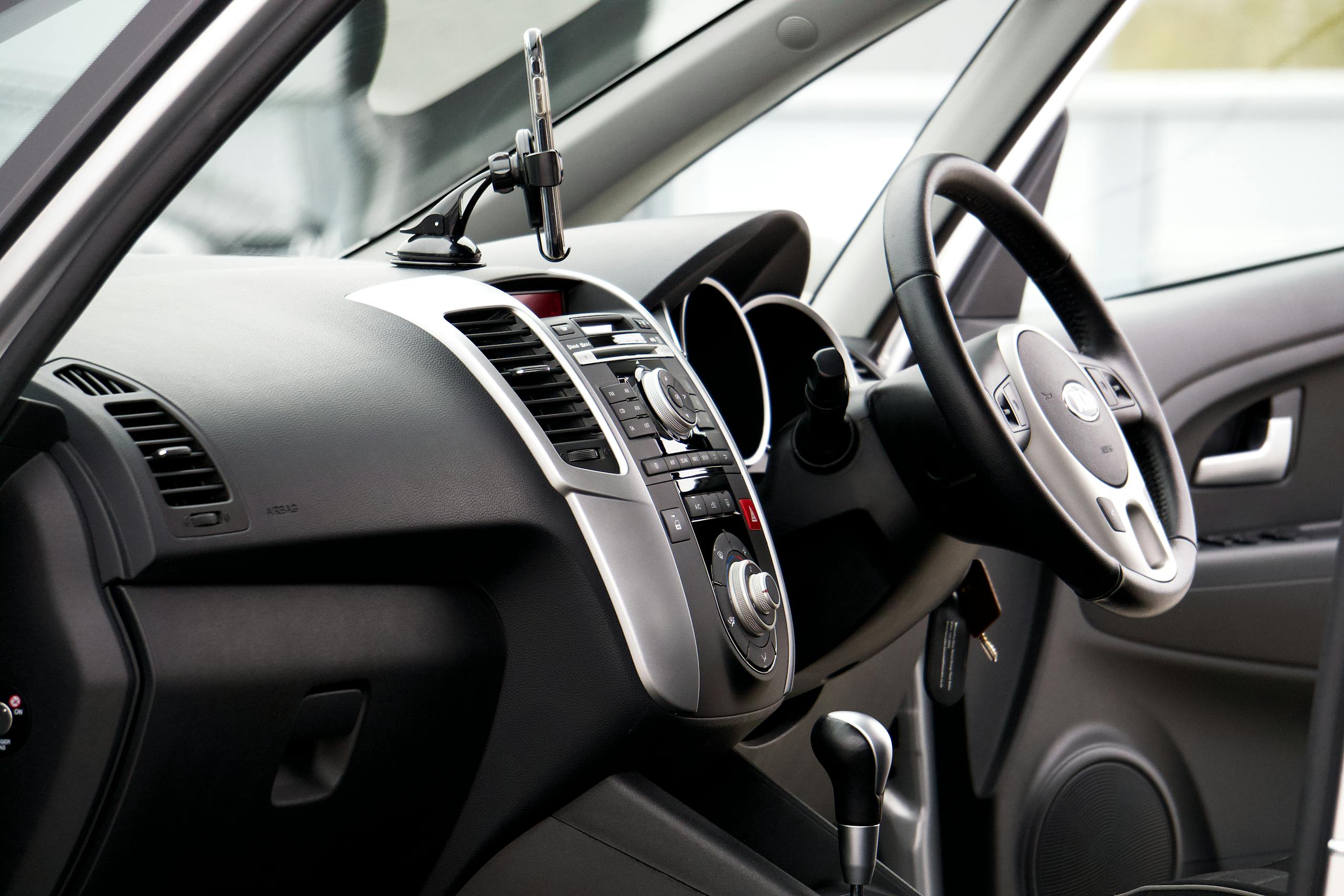 Close-up of a sleek car interior featuring a steering wheel and dashboard with chrome accents.